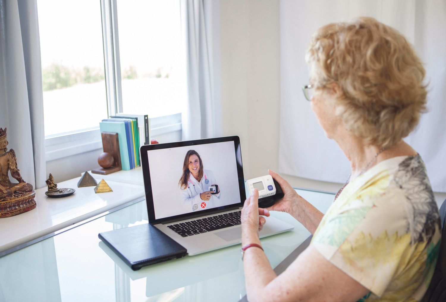 Eine ältere Dame hat eine digitale Sprechstunde an ihrem Laptop mit ihrer Ärztin.